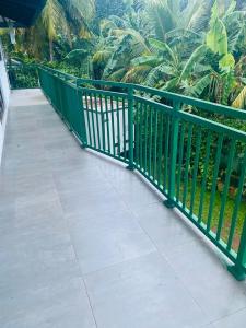 Una barandilla de metal verde en una pasarela con palmeras. en Jana Villa, en Kamburugamuwa