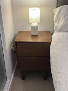 einen Nachttisch mit einer Lampe neben einem Bett in der Unterkunft Modern Studio Retreat with Gym Access in Salford, Manchester in Manchester