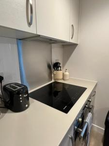 eine Küche mit einer weißen Arbeitsplatte mit einer schwarzen Arbeitsplatte in der Unterkunft Modern Studio Retreat with Gym Access in Salford, Manchester in Manchester