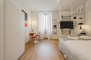 a white bedroom with a bed and a table at Naviglio Suite - Eleganza e Relax a 2 Min dalla M4 e dai Navigli in Milan