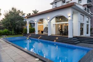 a swimming pool in front of a house at Candolim Pearl - Luxurious 1 BHK Apartment by SoCH Stays in Nerul