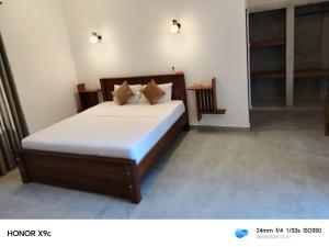 a bedroom with a bed with white sheets and pillows at Lasantha Surf, Madiha in Matara +12 photos