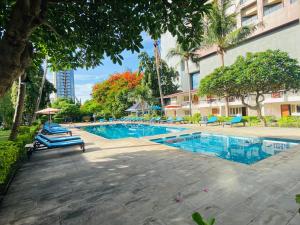 a swimming pool in a building with chairs and trees at Nautical Inn in Pattaya Central