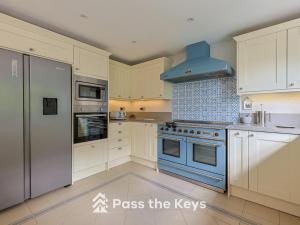a kitchen with white cabinets and a blue stove top oven at Pass the Keys Spacious Family Home - With Parking Garden in Maidenhead