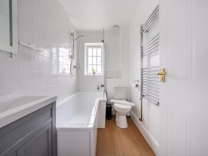 a white bathroom with a tub and a toilet at Pass the Keys Lovely 3 Bed Garden Home - Oxford in Oxford +12 photos