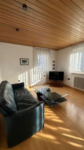 a living room with a leather couch and a glass table at Gästehaus Kaiser in Ostfildern