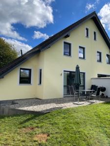 een wit huis met een patio en een tafel en stoelen bij Ferienhaus Schröder Kalterherberg in Monschau