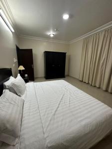 Una cama blanca grande en una habitación con ventana. en Aldaar apartments, en Al Bukayriyah