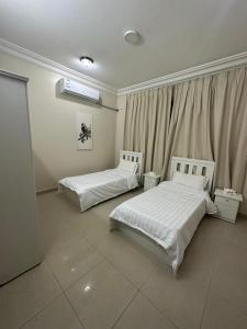 Un dormitorio con dos camas y una ventana. en Aldaar apartments, en Al Bukayriyah
