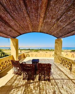 a patio with chairs and a table and a beach at فيلا جاكرندا تونس Jacaranda Villa Tunis in Fayoum
