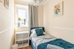 a small bedroom with a bed and a window at Gorgeous 3 bed House - Free Parking near Elizabeth line in Abbey Wood