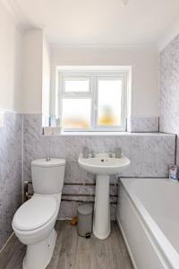 a bathroom with a toilet and a sink and a tub at Gorgeous 3 bed House - Free Parking near Elizabeth line in Abbey Wood