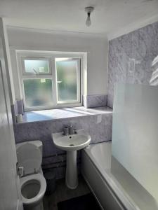 a bathroom with a sink and a toilet and a window at Gorgeous 3 bed House - Free Parking near Elizabeth line in Abbey Wood