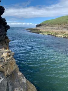 a person sitting on a rock near the water at Central stunning sea view 2 bedroom apartment in Bundoran