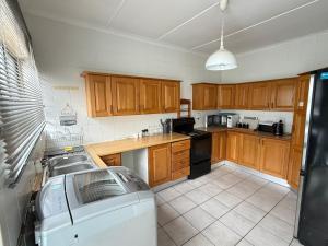 a kitchen with wooden cabinets and a washing machine at JJs At The Sea in Margate