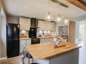 - une cuisine avec un comptoir en bois et un réfrigérateur noir dans l'établissement Rushmoor Cottage, à Colaton Raleigh