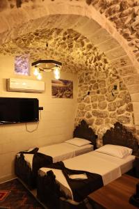 two beds in a room with a stone wall at De MARİA KONAĞI in Mardin
