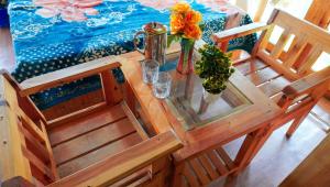 a wooden table with a glass top with flowers on it at Himalayan Homestay Gadagusain in Jibhi