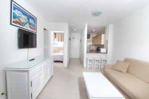 a white living room with a couch and a tv at Apartamentos Tamaragua in Playa del Ingles