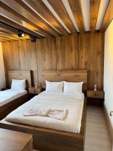 two beds in a room with wooden walls at Lina Apart in Arnavutköy