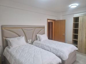 two beds in a bedroom with white sheets and pillows at Almasi Suites at Sandyshore Beach Resort in Kikambala +20 photos