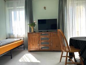 ein Schlafzimmer mit einem Fernseher auf einer Holzkommode mit einem Stuhl in der Unterkunft Apartament na Pogodnie in Stettin