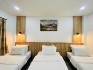 three beds in a room with a painting on the wall at Rendezvous Oldtown Chiangmai in Chiang Mai +149 photos