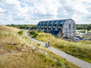 two people riding bikes down a road in front of a building at Residence Westduin in Sint Maartensvlotbrug