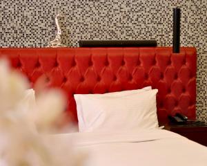 a red padded headboard of a bed with white pillows at Hotel Xperience in Jounieh