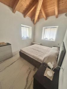 Un dormitorio con una cama y una mesa y dos ventanas. en Ca' Caola Relax, en Pergine Valsugana