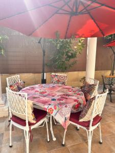 a table and chairs with a red umbrella at Villa IRI Habitación N 2 con un baño compartido , balcón in Pineda de Mar