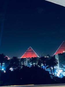 deux pyramides illuminées la nuit par des palmiers dans l'établissement New fort Night Pyramids Hotel, à Giza
