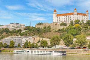 ブラチスラヴァにあるCastle & City, stay in G104の大きな建物の前の川に停泊しているボート
