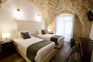 two beds in a room with a stone wall at Petrakis Inn in Jerusalem
