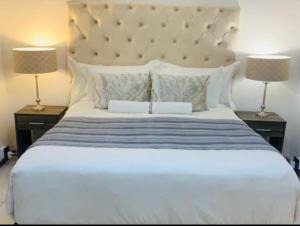 Un dormitorio con una gran cama blanca con dos lámparas. en Grace Lodging and Conference Centre, en Maseru 19 fotos más