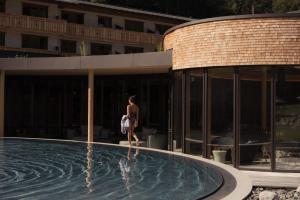 a woman walking next to a swimming pool at Berghotel Schlossanger Alp in Pfronten