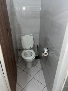 a bathroom with a white toilet in a stall at Modern 1-Bedroom Apartment with AC & Fast WiFi in Accra