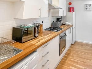a kitchen with white cabinets and a wooden counter top at The Granary House - Long Stayz in Plymouth