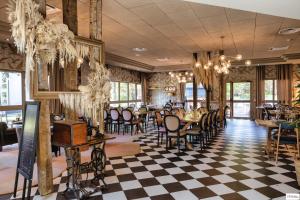 a restaurant with a checkered floor and tables and chairs at Hotel Mercure Parc du Coudray - Barbizon in Le Coudray-Montceaux