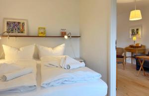 Habitación con cama con sábanas blancas y toallas. en Feriennest mit Terasse, en Süderende