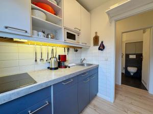 Una cocina con gabinetes azules y un fregadero. en Feriennest mit Terasse, en Süderende 30 fotos más