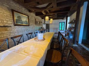 Un comedor con una mesa larga y sillas. en Le Moulin des Marguerites, en Saint-Père