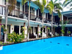 a swimming pool in front of a hotel with palm trees at Santino Boutique in Mirissa