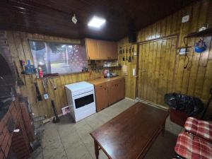 a kitchen with wooden walls and a table and a stove at Cabana Antonio&Thea in Poiana Ţapului
