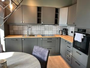 a kitchen with gray cabinets and a sink and a table at Riddertunets utsikt til Slettefjell in Beitostøl