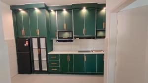 a kitchen with green cabinets and a black refrigerator at Sky28 - Sireh Residence in Kota Bharu