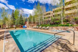 a swimming pool with chairs and a building at Sun Vail 24B in Vail