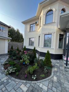 una casa con un jardín de flores en el patio delantero en Cozy, en Bishkek