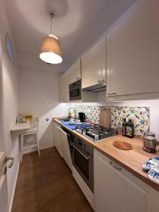 a kitchen with white cabinets and a stove top oven at Casa vista Faraglioni Capri 2 in Capri