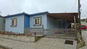 a blue house with a fence in front of it at Casa Ribeiro in Canguçu